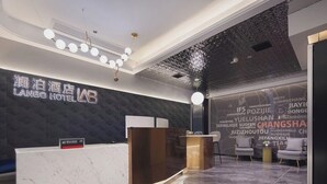 A hotel reception area with a marble counter, a dark textured wall, and a ceiling with a light fixture.