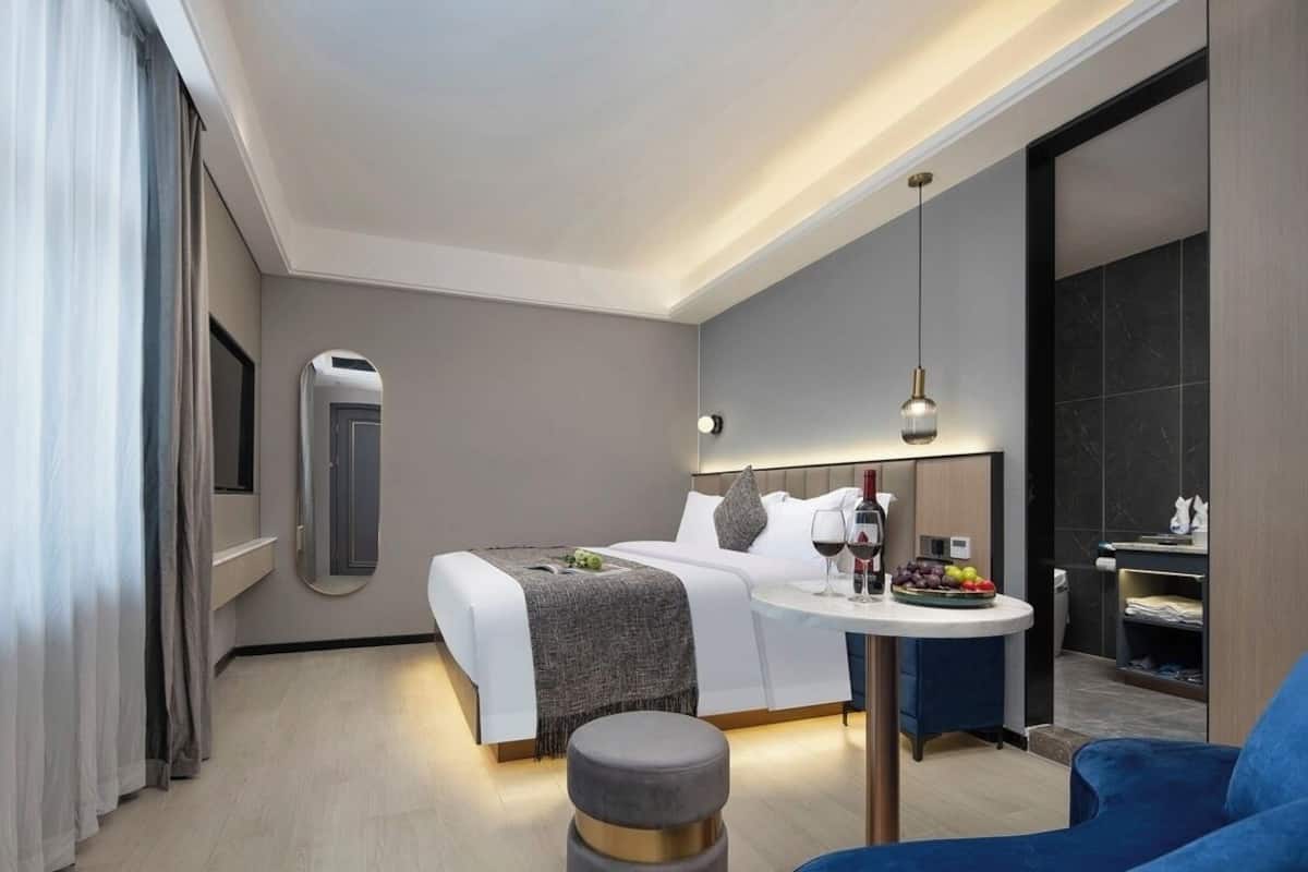 Una habitación de hotel moderna con una cama, una mesita de noche y una pequeña mesa redonda con una silla.
