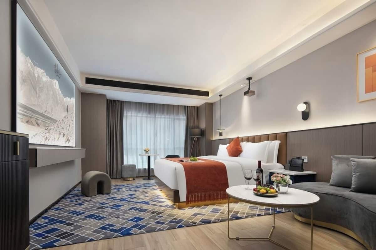 Una habitación de hotel moderna con cama, mesita de noche y sofá.