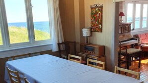 Een eetruimte met een tafel, stoelen, een lamp en uitzicht op zee.