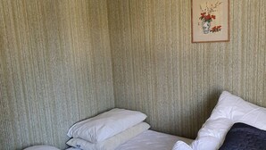Een kamer met een bed, twee kussens, een lijst met een afbeelding aan de muur, en een structuurmuur.