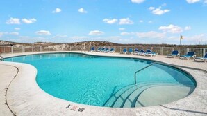 A swimming pool with lounge chairs and a flag.