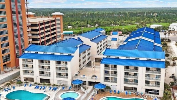 A multi-story hotel with a rooftop pool and a large swimming pool.