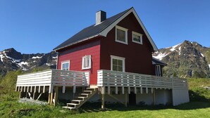 Ett rött hus med en vit veranda och en trappa som leder upp till den.
