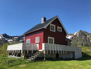 A red house with a white porch and a staircase leading up to it.