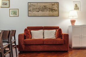Ein Zimmer mit einem roten Sofa, einem weißen Schrank und gerahmten Bildern an der Wand.