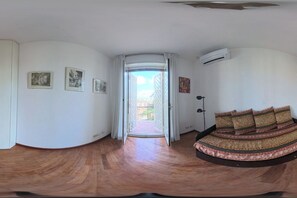 Ein Zimmer mit einem gewölbten Bett, einer Tür zu einem Außenbereich und Blick auf Gebäude durch die Tür.