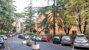 Un parking avec des voitures, des arbres et des immeubles d’habitation en arrière-plan.