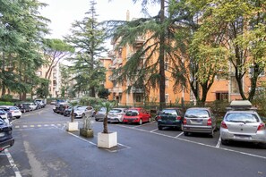 Ein Parkplatz mit Autos, Bäumen und Wohngebäuden im Hintergrund.