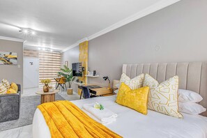 Ein Hotelzimmer mit Bett, Schreibtisch, Stuhl und einem kleinen Tisch mit einer Vase.
