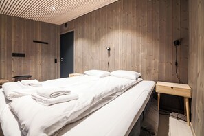 Un dormitorio con una cama grande, una mesita de noche y paneles de madera en la pared.