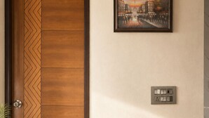 Una puerta de madera con un diseño en patrón de chevron, un cuadro enmarcado de un paisaje urbano y un enchufe de pared.