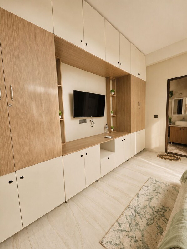 A modern room with a built-in TV, wooden cabinets, a small sink, and a patterned rug. - Moksha Zen Luxury 2BHK|Epic Rooftop Mountain view (Rishikesh)