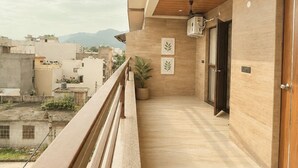 Un balcón con barandilla de madera, una planta en maceta y cuadros en la pared.