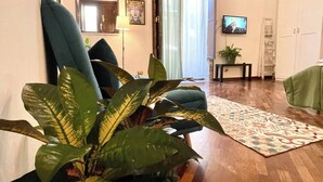 Un salon avec un plafond en bois, une télévision, un canapé, une table basse et une grande plante en pot.