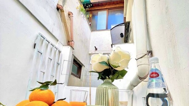 Une table avec des oranges, une tasse de café, un verre de jus d’orange, une bouteille d’eau et une cuillère, le tout posé sur une nappe bleue.