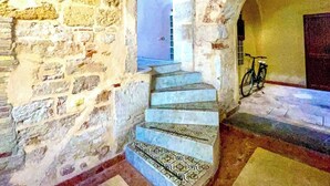 Un escalier en pierre menant à une porte, un vélo et un sol à motifs.