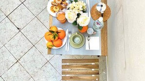 Une table à manger avec des chaises en bois, une assiette de nourriture et un verre de jus d’orange.