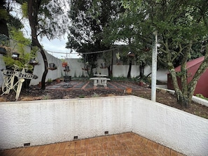 A courtyard with a stone bench, hanging planters, and a bicycle sculpture.