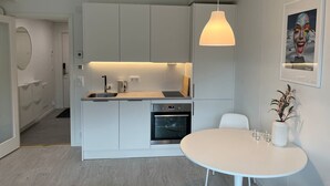 Una cocina moderna con encimera blanca, horno empotrado y una lámpara colgante.