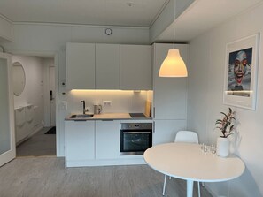 Una cucina moderna con piano di lavoro bianco, forno integrato e lampada a sospensione.