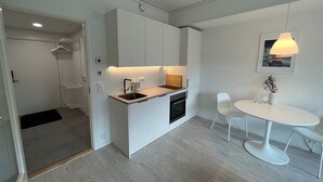 Una cocina moderna con armarios blancos, horno integrado y un comedor con mesa y sillas blancas.