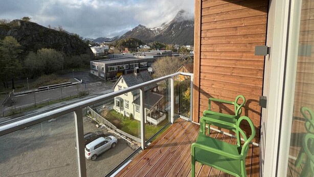 Un balcón con vistas a una montaña, una carretera y un edificio.
