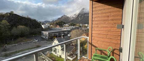 A balcony with a view of a mountain, a road, and a building.