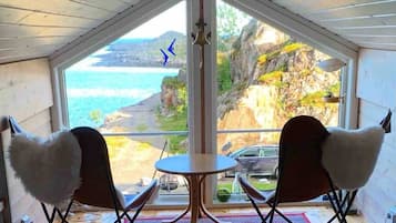Ein Zimmer mit einem großen Fenster, zwei Stühlen, einem kleinen Tisch und einer Türklingel.