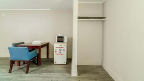 Una habitación con una mesa de comedor, una silla azul, un microondas blanco y un pilar blanco.
