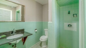 Un baño con lavamanos, inodoro y zona de ducha.