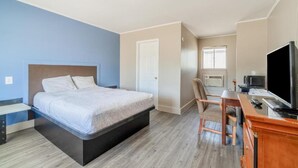 Una habitación de hotel con una cama, un escritorio con una computadora, un televisor y una ventana.