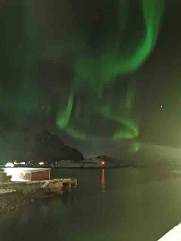 Ein Nachtbild einer Küstenlandschaft mit Leuchtturm und Anlegesteg.