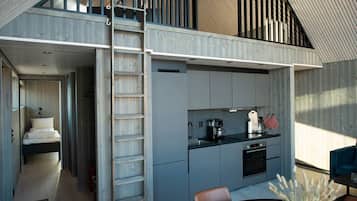 Una cocina compacta con horno integrado, cafetera y comedor con mesa y sillas.