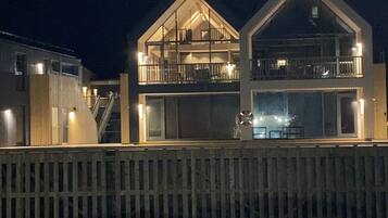 Un bâtiment à deux étages doté d’un balcon à l’étage supérieur, d’un escalier menant à l’étage supérieur et d’une clôture en bois au premier plan.