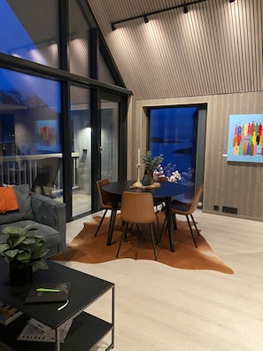 A modern dining area with a round table, chairs, and a glass partition.