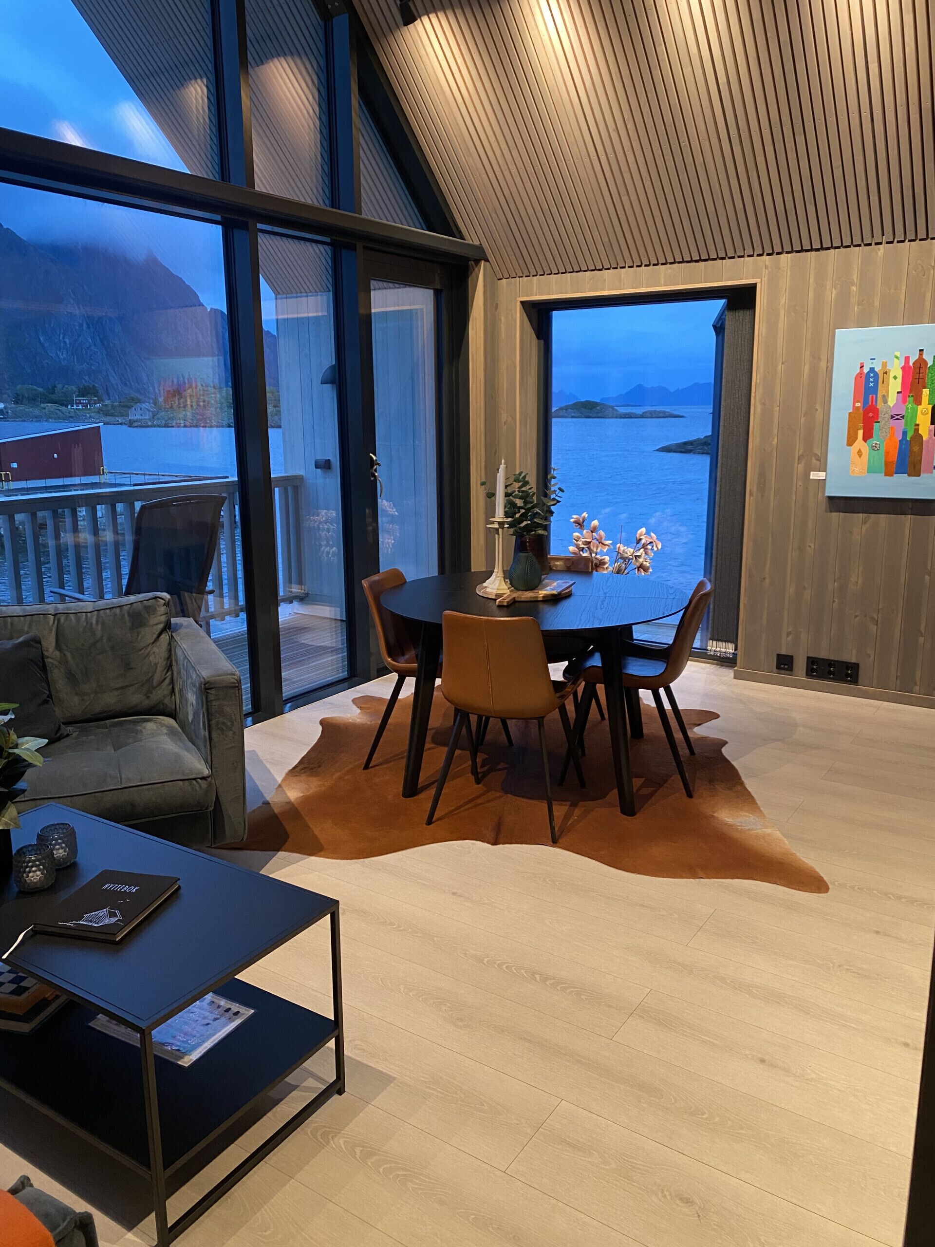 Un interior modern amb zona de menjador, sofà i vista al mar.