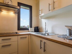Eine Küche mit Fenster, Edelstahlspüle und Schränken.