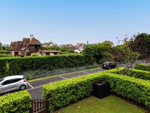 A residential street with a Tudor-style house, a parked car, and a hedge-lined driveway. - Les Manoirs by Interhome (Deauville-Trouville)