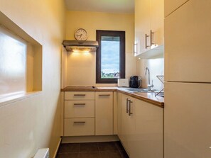 A compact kitchen with a clock, a window, and a coffee maker. - Les Manoirs by Interhome (Deauville-Trouville)