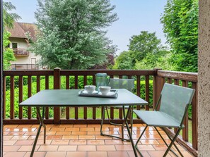 Eine Terrasse mit Tisch, Stühlen, einer Karaffe und einer Tablett mit Tassen und Untertassen.