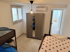 Ein Schlafzimmer mit Bett, Kleiderschrank, Schreibtisch und Fenster.