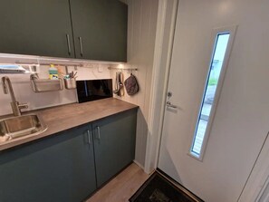 A kitchen with a sink, stove, and cabinets. - Panoramic seaview cabin for two persons by the sea (Flakstad)