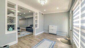 A hallway with a staircase, a living room with a sofa, and a white cabinet. - Spacious Newly Renovated Scenic Bay View Home Sleeps 1-8, Free Parking very safe (Ventnor City)