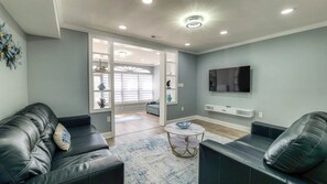 A modern living room with leather sofas, a round coffee table, a flat-screen TV, and a decorative wall piece. - Spacious Newly Renovated Scenic Bay View Home Sleeps 1-8, Free Parking very safe (Ventnor City)