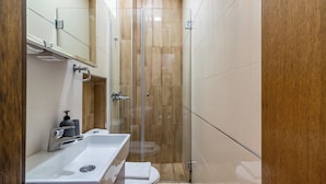 Un baño moderno con ducha de vidrio, lavamanos blanco y retrete.
