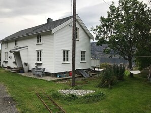 Una casa blanca con porche, una pequeña terraza y vista a un lago.