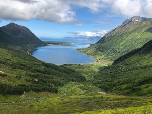 Paisaje montañoso con un lago, zonas boscosas y cielo despejado.
