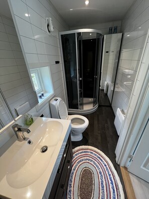 Une salle de bain moderne avec un lavabo, des toilettes et une douche à l’italienne, le tout de couleur blanche.