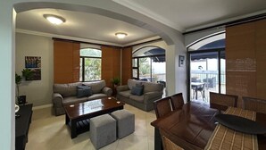 Un salón amplio con un conjunto de sofás, una mesa de centro y una mesa de comedor con sillas.